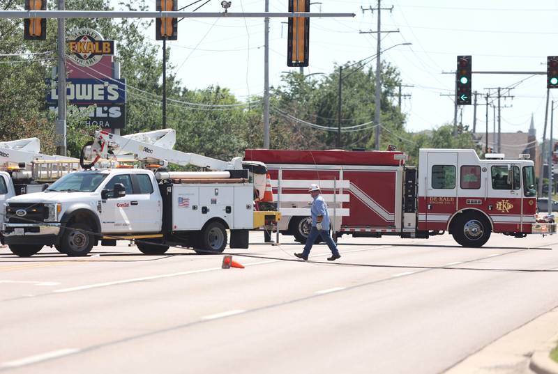 A ComEd worker walks near downed powerlines after a semi-trailer truck struck and pulled down the wires onto Sycamore Road near Walmart Tuesday, June 21, 2022. The road was shut down from the Walmart entrance to Barber Greene Road.