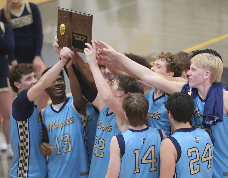 Members of the Marquette boys basketball team hoist the Tri-County Conference Championship plaque on Friday, Jan. 30, 2026 at Putnam County High School.