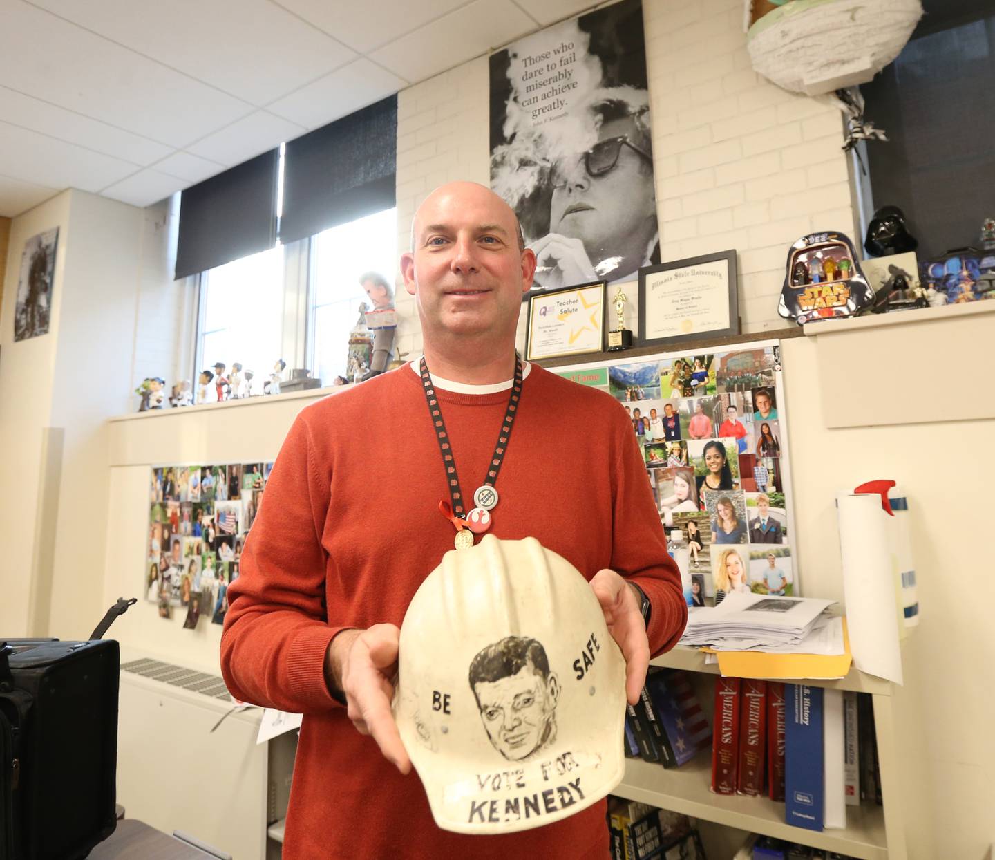 Mr. Troy Woods, history instructor at La-Salle-Peru Township High School, holds a campaign helmet that reads "Be safe Vote for Kennedy" printed on it in his classroom on Wednesday, Dec. 7, 2022 at L-P High School. Woods obtained the helmet from the Suarez family. John Suarez Sr. painted the helmet and was passed down to his son John who gave it to Troy. Woods is donating it to the JFK Presidential Museum and Archives in Boston Mass.