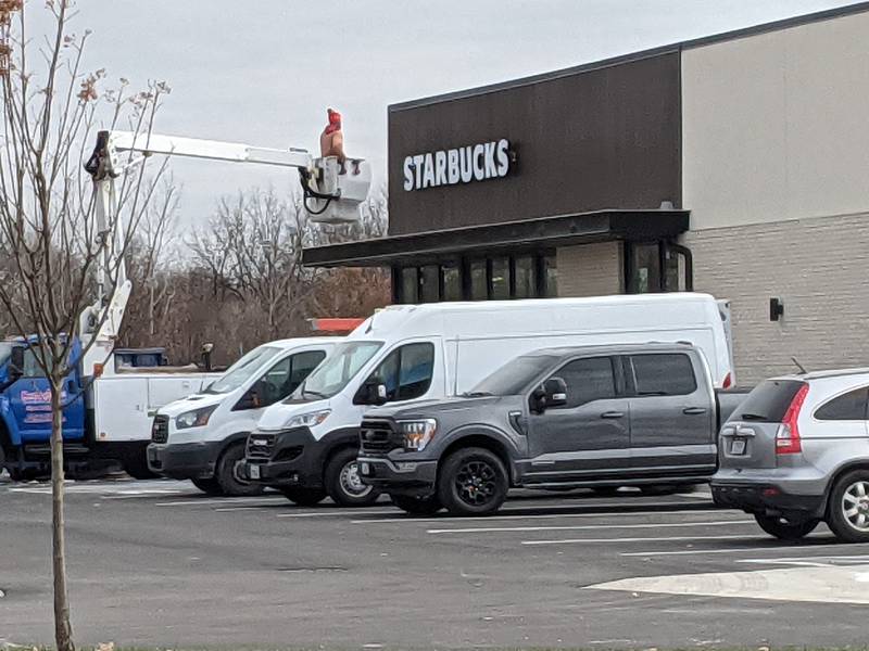 A worker on Dec. 6 hangs up a sign for the new Starbucks restaurant that is expected to open by the end of the month along Orchard Road, just north of Route 34.