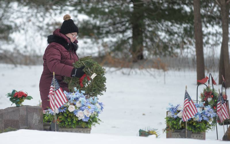Laurie Carlin-Perry places a wreath on a veteran's grave during the Wreaths Across America program at the Daysville Cemetery, southeast of Oregon, on Saturday, Dec. 13, 2025.