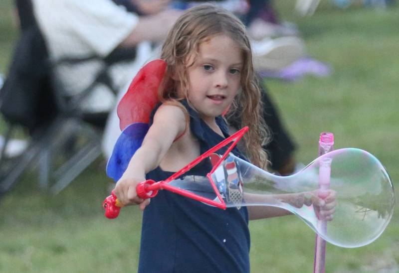 Brinley Phillips of Oglesby, creates a giant bubble before the "Rock the River" fireworks on Thursday, July 3, 2025 on Water Street in Peru.