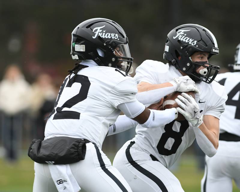 Fenwick's Jamen Williams (12) hands the ball off to teammate Jake Thies (8) during the 6A semifinals game on Saturday Nov. 22, 2025, held at Nazareth Academy High School in La Grange Park.