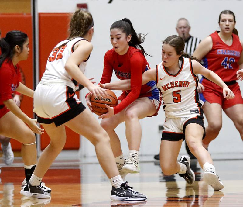 Dundee-Crown’s Charlotte Stewart grabs a loose ball between McHenry's Lucy Jones and Gaby Grasser during a Fox Valley Conference girls basketball game on Tuesday, Dec. 12, 2023, at McHenry High School.