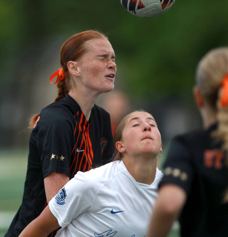 St. Charles East's Reese Kyle heads the ball over St. Charles North's Maddie Room during a Class 3A Glenbard West Sectional semifinal game on Tuesday, May 27, 2025 in Glen Ellyn.