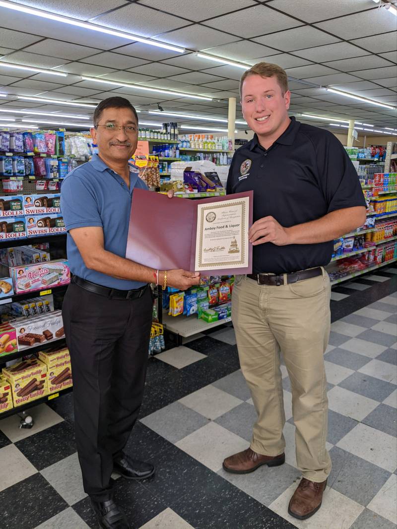 SanJay Desi, left, owner of Amboy Food and Liquor, receives a certificate of honor from State Rep. Bradley Fritts for his contributions to the community.