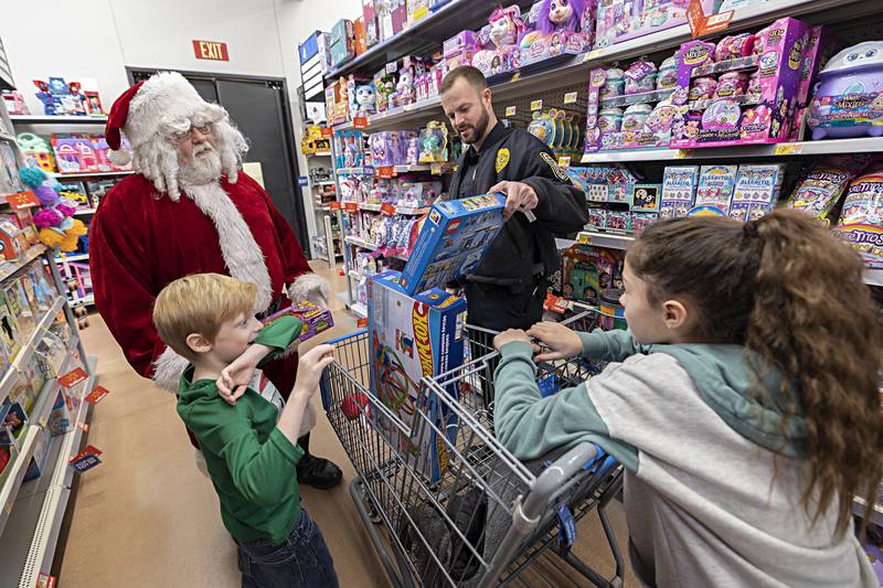 Santa, Dixon officer Ryan Bivins and daughter Marley, 10, help Owen Wilhite, 7, pick out gifts Saturday, Dec. 9, 2023 at Dixon Walmart.