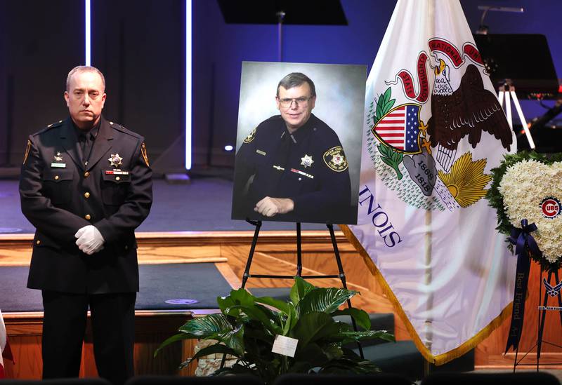 A DeKalb County sheriff's deputy guards the casket of former DeKalb County Sheriff Roger Scott as a photo of Scott stands nearby during his visitation Thursday, March 6, 2025, at Bethany Road Bible Church in DeKalb. Scott, who was the county sheriff for more than 30 years, died on February 23 at the age of 78.