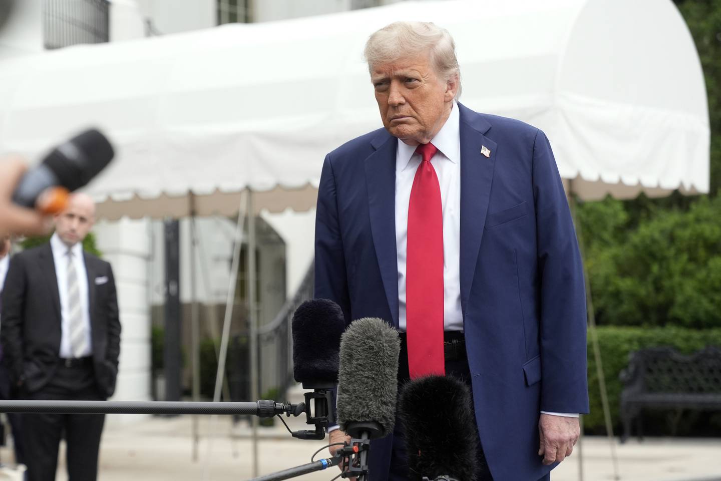 President Donald Trump listens to a question from a reporter as White House Deputy Chief of Staff Stephen Miller listens before departing the White House on his way to attend the G7 Summit in Canada, Sunday, June 15, 2025, in Washington. (AP Photo/Manuel Balce Ceneta)