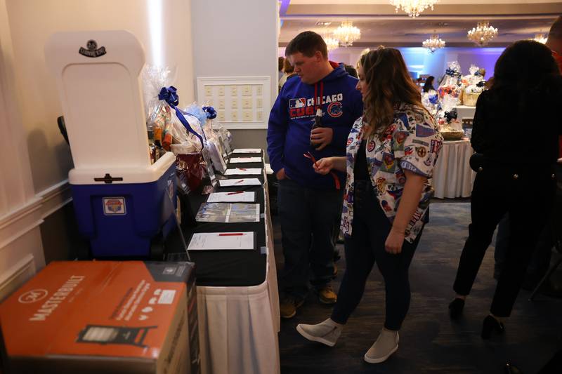 Alex Bromeland and Kyleigh Carie of Plainfield look over the silent auction items at the Shorewood HUGS "Sweet Home Chicago" chocolate ball fundraiser in Joliet on Saturday, February 4, 2023.