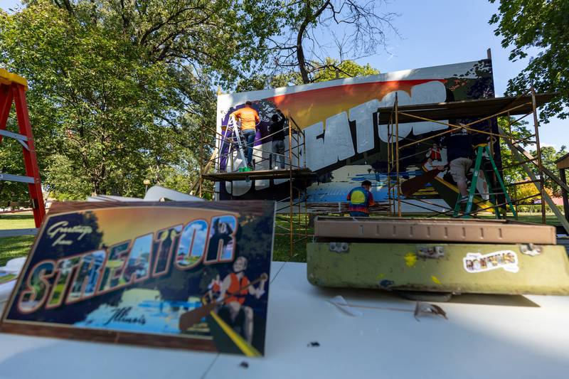 Unfinished Streator mural sits behind table holding blueprint for the project on Thursday, Sept. 11, 2025 at City Park in Streator.