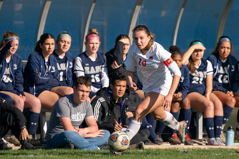 Oswego’s Anna Johnson (20) plays the ball in front of the Oswego East bench during a soccer match at Oswego East High School on Thursday, Apr 6, 2023.