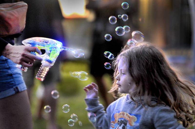 Three-year-old Everleigh Zidlicky of Montgomery gets attacked with her own light up bubble gun during the 83rd Montgomery Fest on Saturday, Aug. 19, 2023.