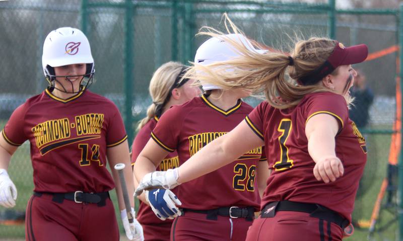 Richmond-Burton’s Rockets prepare to greet Mia Spohr after she belted a home run in varsity softball at Marengo Tuesday.