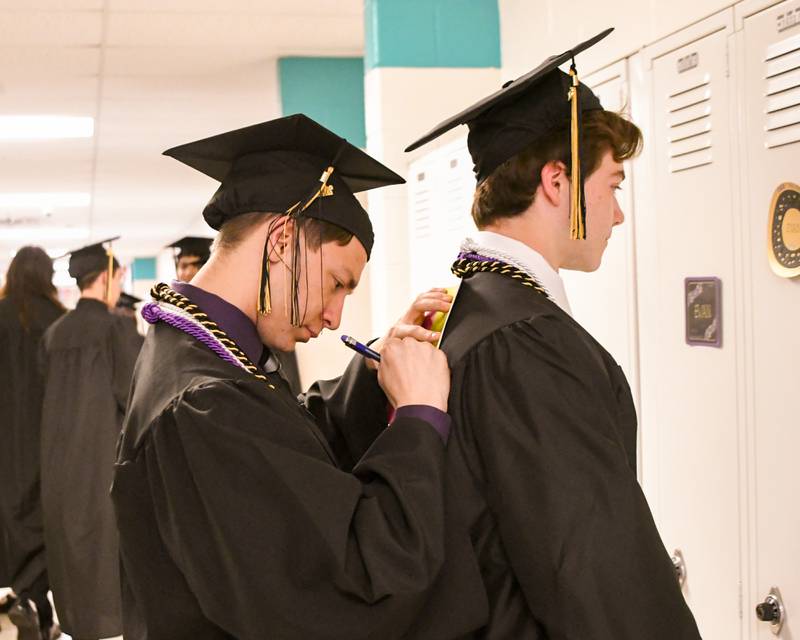 Sycamore senior Colin Mills (left) gets some help from fellow graduate Aidan Gagalski to sign a card on Sunday, May 24, 2026, before the start of the Class of 2026 Commencement held at Sycamore High School.