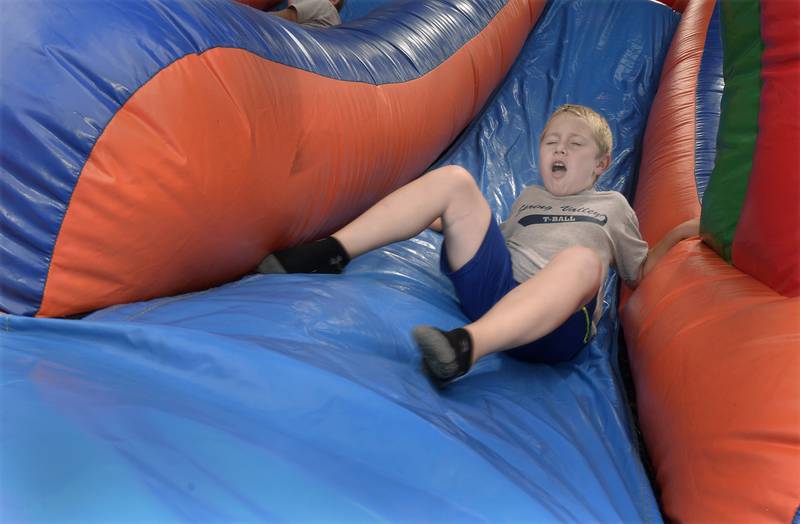 Greyson Smith has a hard landing on a bounce house slide Saturday during Spring Valley’s Summerfest.