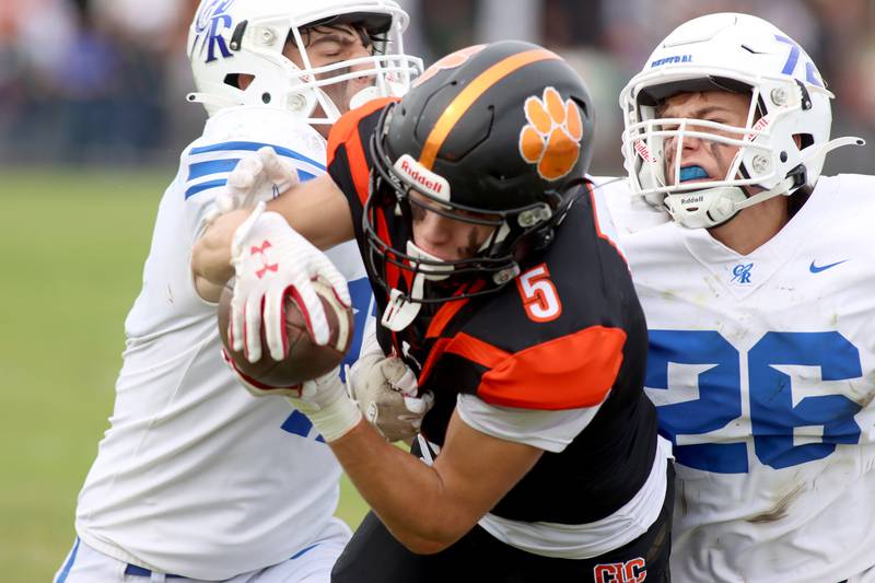 Crystal Lake Central’s Casen Noennig, center, reels in a touchdown reception as Burlington Central’s Chase Powrozek, left, and Liam Ballantyne, right, defend in varsity football at Crystal Lake Saturday.