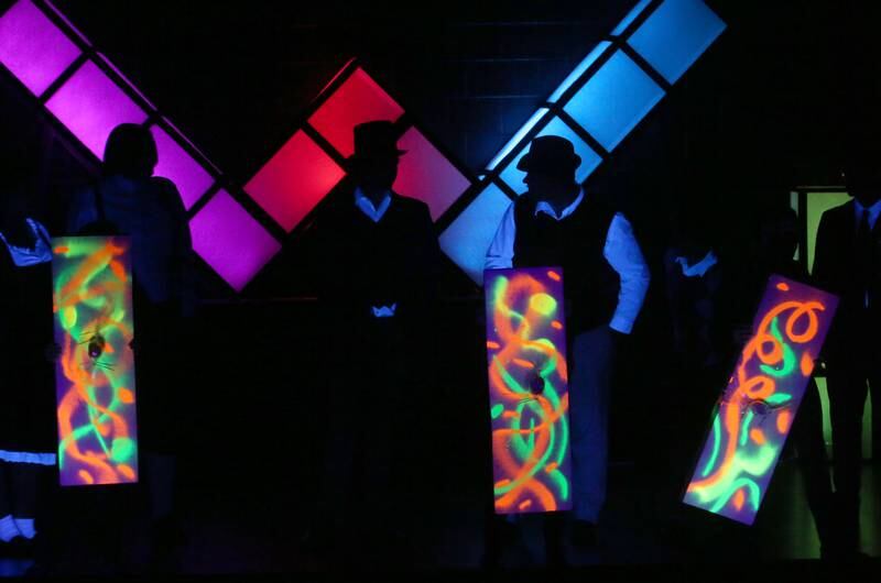 Actors use light up signs that glow under a black light during a performance of Willy Wonka on Thursday, March 16, 2023 at Putnam County High School.