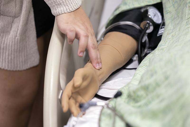 An aspiring health care student practices checking for a pulse Friday, April 17, 2026, on an interactive mannequin.