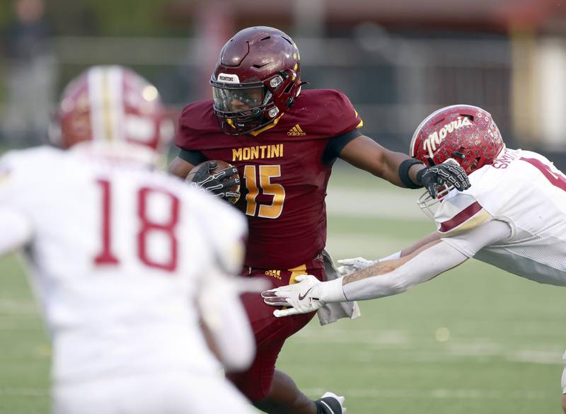 Montini's Charles Flowers (15) looks to slide past Morris' Mick Smith (4) during the IHSA Class 4A semifinals football playoff game Saturday, Nov. 22, 2025 in Lombard.