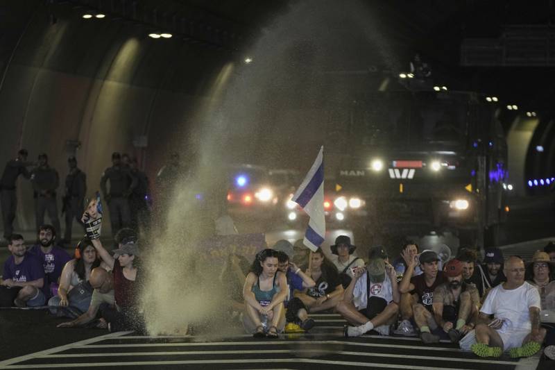 Police uses water canon to disperse demonstrators blocking a road during a protest demanding the immediate release of hostages held by Hamas and calling for the Israeli government to reverse its decision to take over Gaza City and other areas in the Gaza Strip, in Jerusalem, Sunday, Aug. 17, 2025. (AP Photo/Mahmoud Illean)