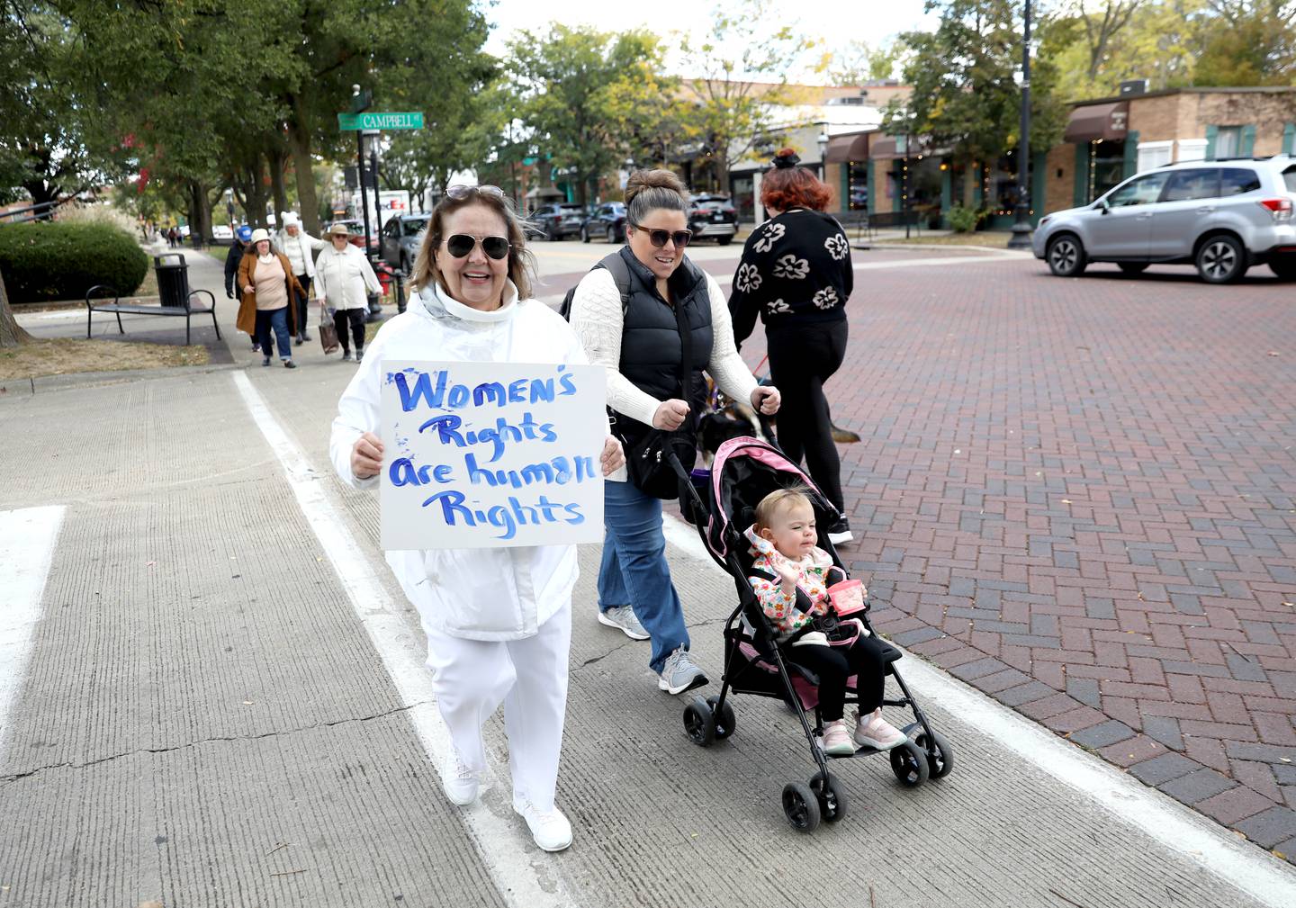 Kim Young (left) of Batavia and Lindsey Morris of Elgin, with her 22-month-old daughter Lily, participate in the Roe the Vote and March to the Polls from the Kane County Courthouse to the Kane County Clerk’s office in Geneva on Tuesday, Oct. 15, 2024.