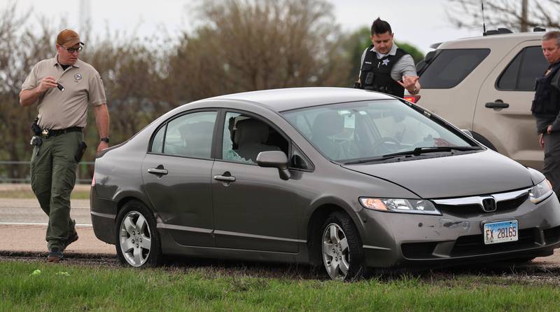 Law enforcement officials look into a Honda sedan with a shattered window in the westbound lanes of Interstate 88 Monday, April 27, 2026, as they investigate an incident on I-88 just west of Keslinger Road in Maple Park.