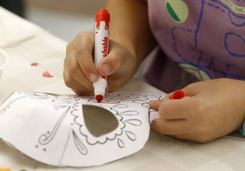 Violet Wargaski, 9, colors her mask as children make masks on Wednesday, Oct. 23, 2024, during at Kids Crafternoon at the Harvard Diggins Library. Children were able to chose between several Halloween themed masks to make.