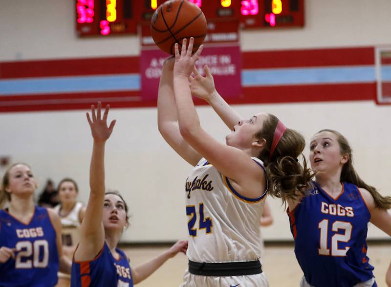 Johnsburg's Mackenzie McQuistion, center, drives to the basket against Genoa-Kingston's Avery Walters, left, and Ally Poegel, right, during a IHSA Class 2A Regional semifinal basketball game Monday evening, Feb. 14, 2022, between Johnsburg and Genoa-Kingston at Marian Central High School.