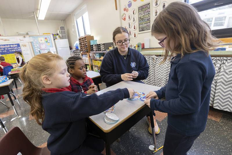 Grace Drew, a Newman freshman, plays a card game with Dixon St. Mary’s kindergarteners Mia (left), Amalie a dn Harlow Wednesday, Jan. 29, 2025. NHS students visited the school to play games with the kids in celebration of Catholic Schools Week.