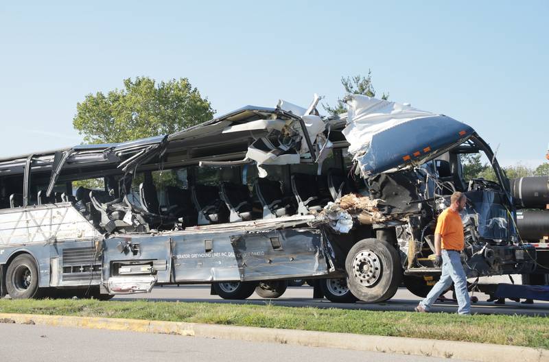 A worker helps clear the wreckage of a Greyhound bus that collided with tractor-trailers on the exit ramp to a rest area on westbound Interstate 70 in Highland, Ill., on Wednesday, July 12, 2023.