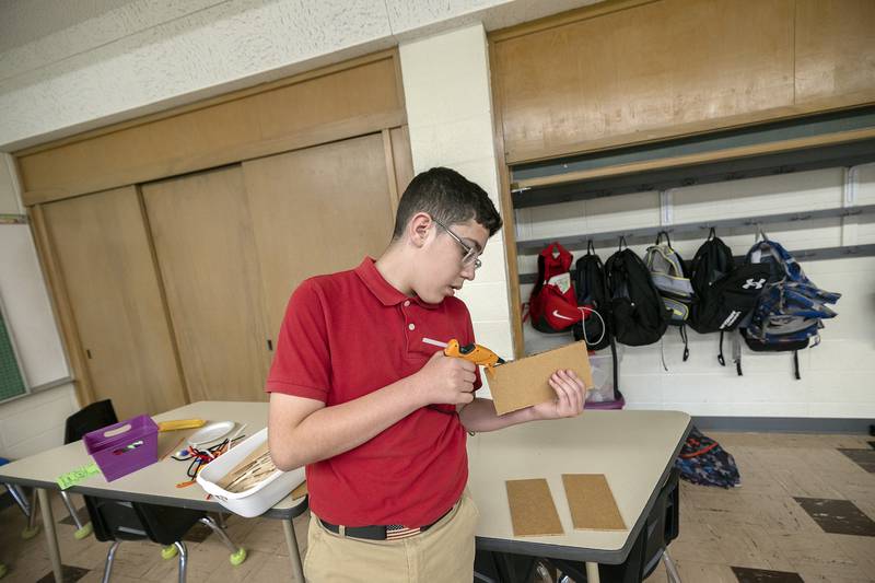 Carlos Farias, St. Mary’s seventh grader, glues together a 3D art work Friday, May 9, 2025. The school had four art stations available with the students being able to choose two.