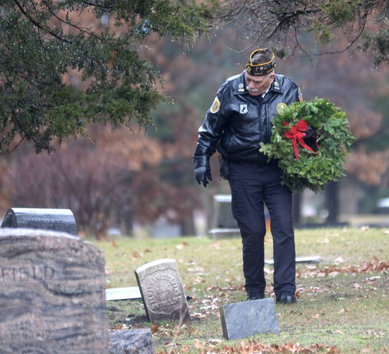 Oregon VFW member and Vietnam War veteran John Tuttle of Oregon, carries a wreath to a veteran's grave at the Wreaths Across America event at Daysville Cemetery. east of Oregon, on Saturday, Dec. 16, 2023.
