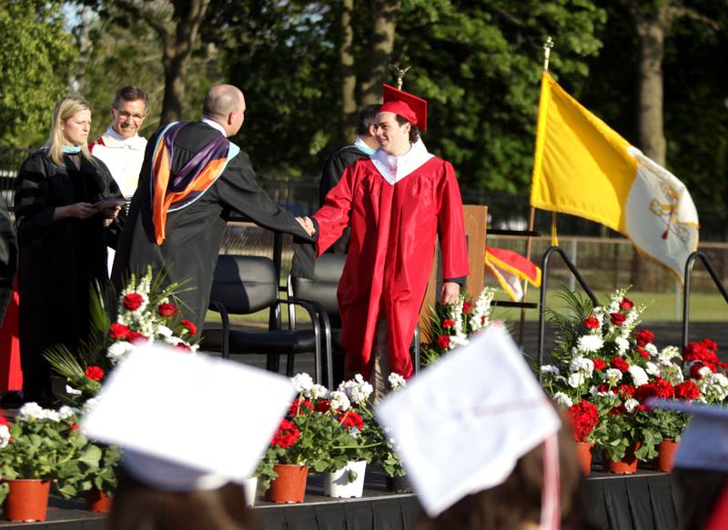 Benet graduate Daniel Cannon walks across the stage to receive his diploma during the school’s commencement ceremony in Lisle on Thursday, May 25, 2023.
