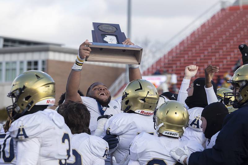 Althoff Catholic’s Jason Dowell raises the trophy after their  52-14 win over Lena-Winslow Friday, Nov. 29, 2024, in the class 1A football state final.