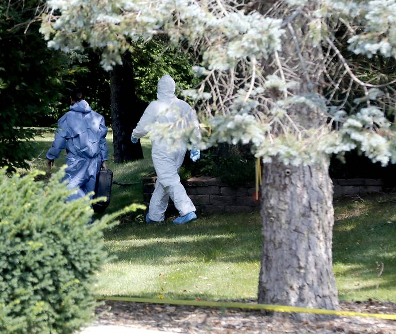 Investigators walk around the side of a home in 5800 block of Wild Plum Road in unincorporated Crystal Lake on Thursday, Aug. 10, 2023, as the McHenry County Sheriff's office continued to investigate the scene where four family members, including three females and a male “aggressor,” were killed Wednesday.
