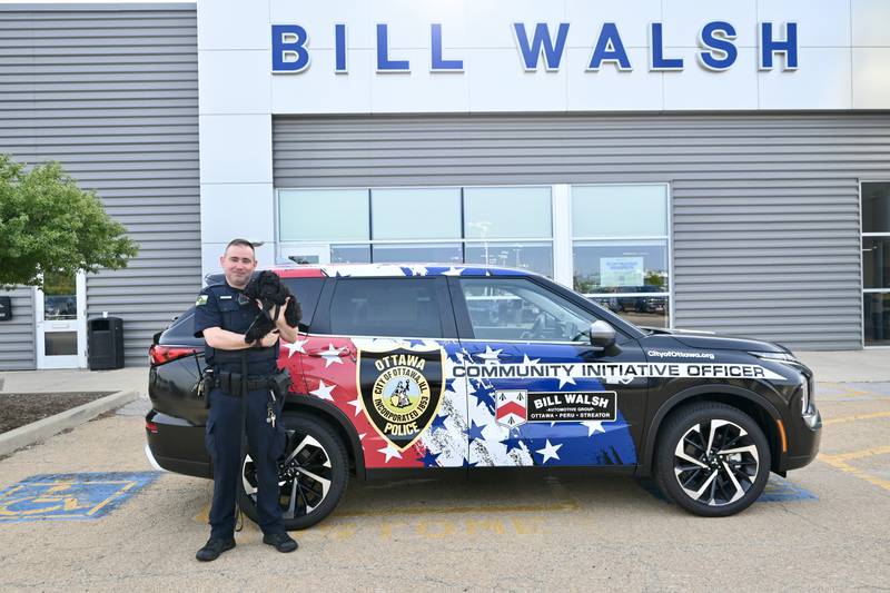 Community Initiative Officer Tyler Brewer stands with his new partner K9 Rookie in front of his new vehicle on Wednesday Aug. 9, 2023.