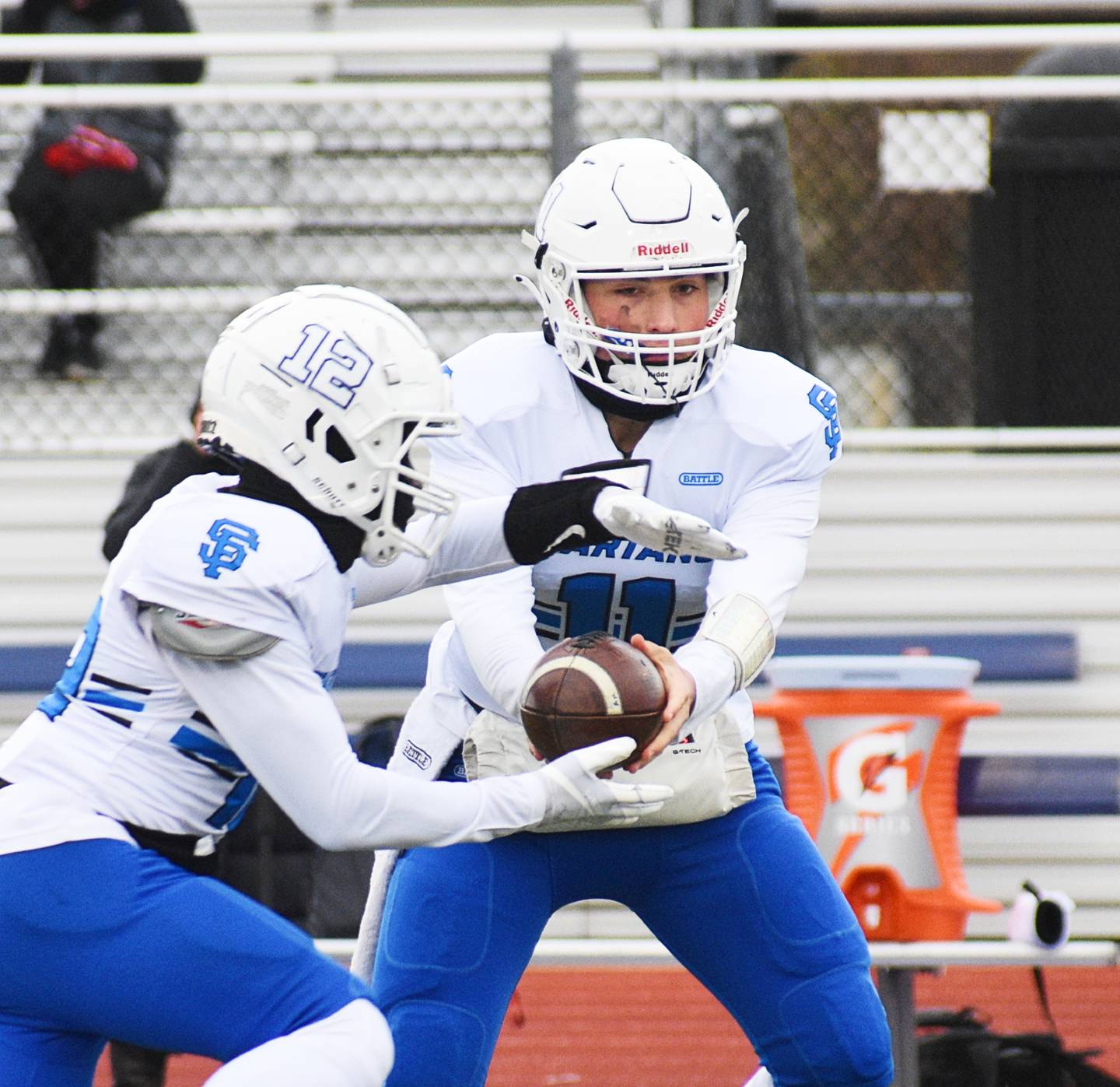 Wheaton St. Francis quarterback Alessio Milivojevic hands the ball to running back Amari Head during Saturday’s Class 4A state quarterfinal game against Rochelle.