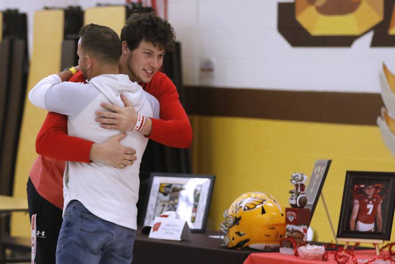 Jacobs' Grant Stec hugs Jacobs football coach Brian Zimmerman before he signs his National Letter of Intent to attend and play football at the University of Wisconsin on Wednesday, Dec. 20, 2023, at the Jacobs High School in Algonquin.