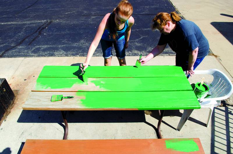 Megan Carney and her mom, Anita, paint a picnic table at Kreider Services in Dixon during a previous United Way of Lee County's Day of Caring.
