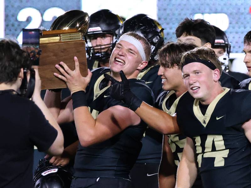 Sycamore players hoist the trophy after the win over DeKalb Friday, Aug. 29, 2025, after the FNBO Challenge in Huskie Stadium at Northern Illinois University.