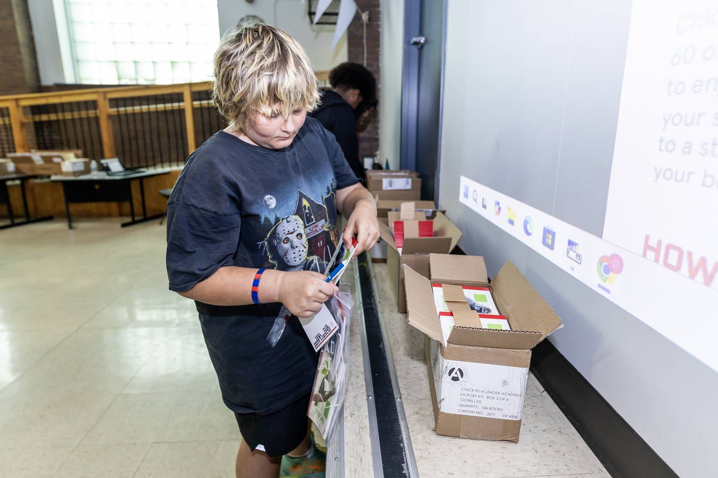 Josh Socha packs a bag with books that will be given to four to eight-year-old children during the Chick-fil-A Leader Academy at Lincoln School on Sept. 9, 2025.