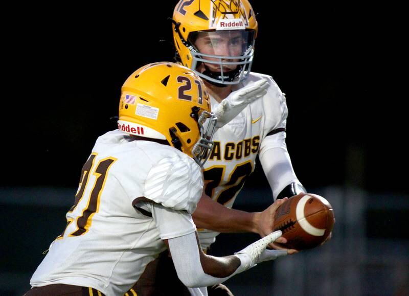 Jacobs’ Connor Goehring, back, hands off to Mike Cannady in varsity football on Friday, Sept. 20, 2024, at Al Bohrer Field on the campus of Cary-Grove High School in Cary.