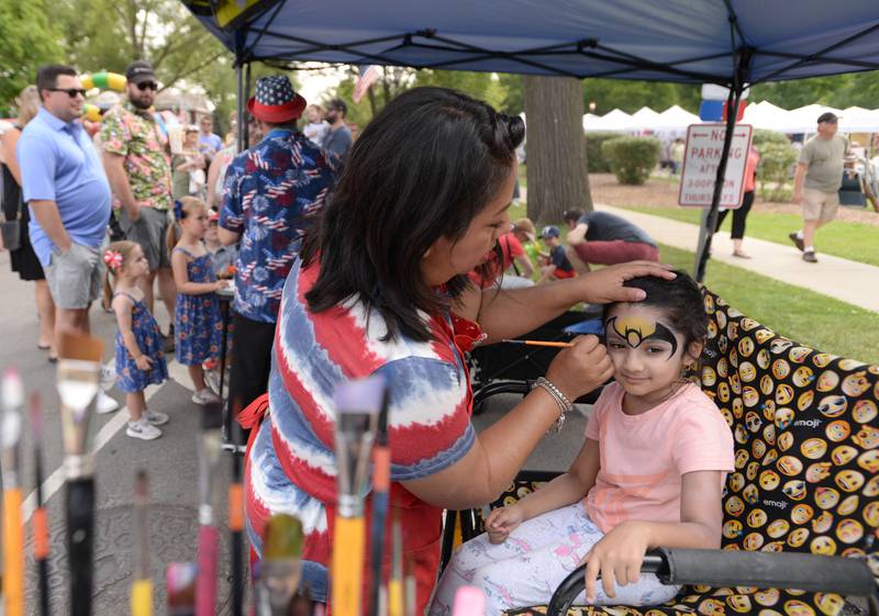 Lina Syed of Bloomingdale gets Batman wings painted on her face by Yamel Azcoitia of Round Lake during the Hinsdale 4th of July Family Festival Tuesday June 4, 2023.