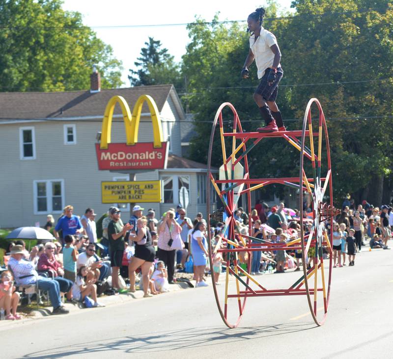 A paid performer stands on top of a big wheel in the Harvest Time Parade held during Autumn on Parade on Sunday, Oct. 5, 2025 in Oregon.