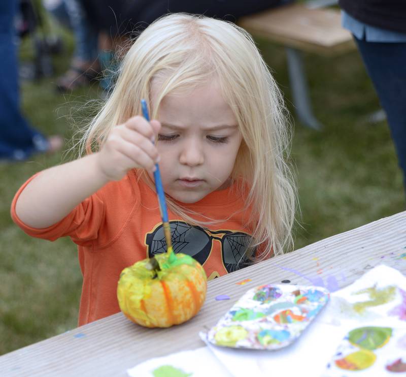 Emma Meseke decorates a small pumpkin Saturday, Sept. 28, 2024, at the Jordan block during the annual Scarecrow Fest in Ottawa.