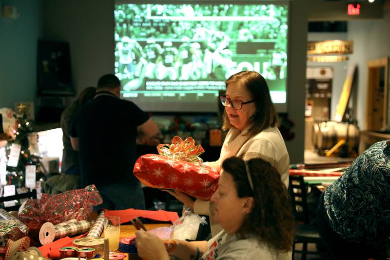 Marge Brown holds one of the gifts during a gift wrapping party for clients of the Association for Individual Development (AID) hosted by the Batavia Rotary Club on Thursday, Dec. 12, 2024 at Brother Chimp Brewing in North Aurora.