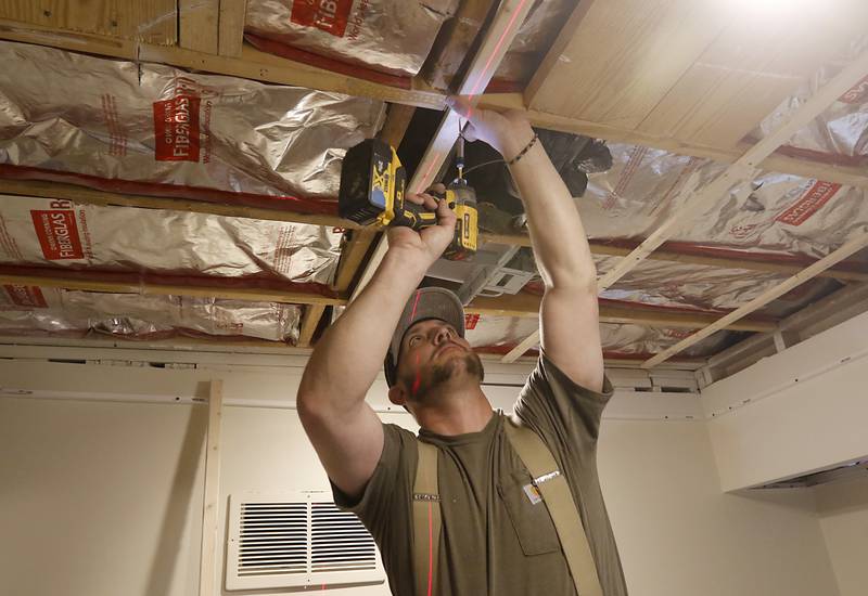 Matt Raine installs a new drop ceiling in one of the bathrooms at Golden Age Cinemas McHenry Outdoor Theater on Wednesday, April 12, 2023, as the theater, in partnership with The Bremer Team, are making over the concession stand and bathrooms before the theater's May 5 opening.