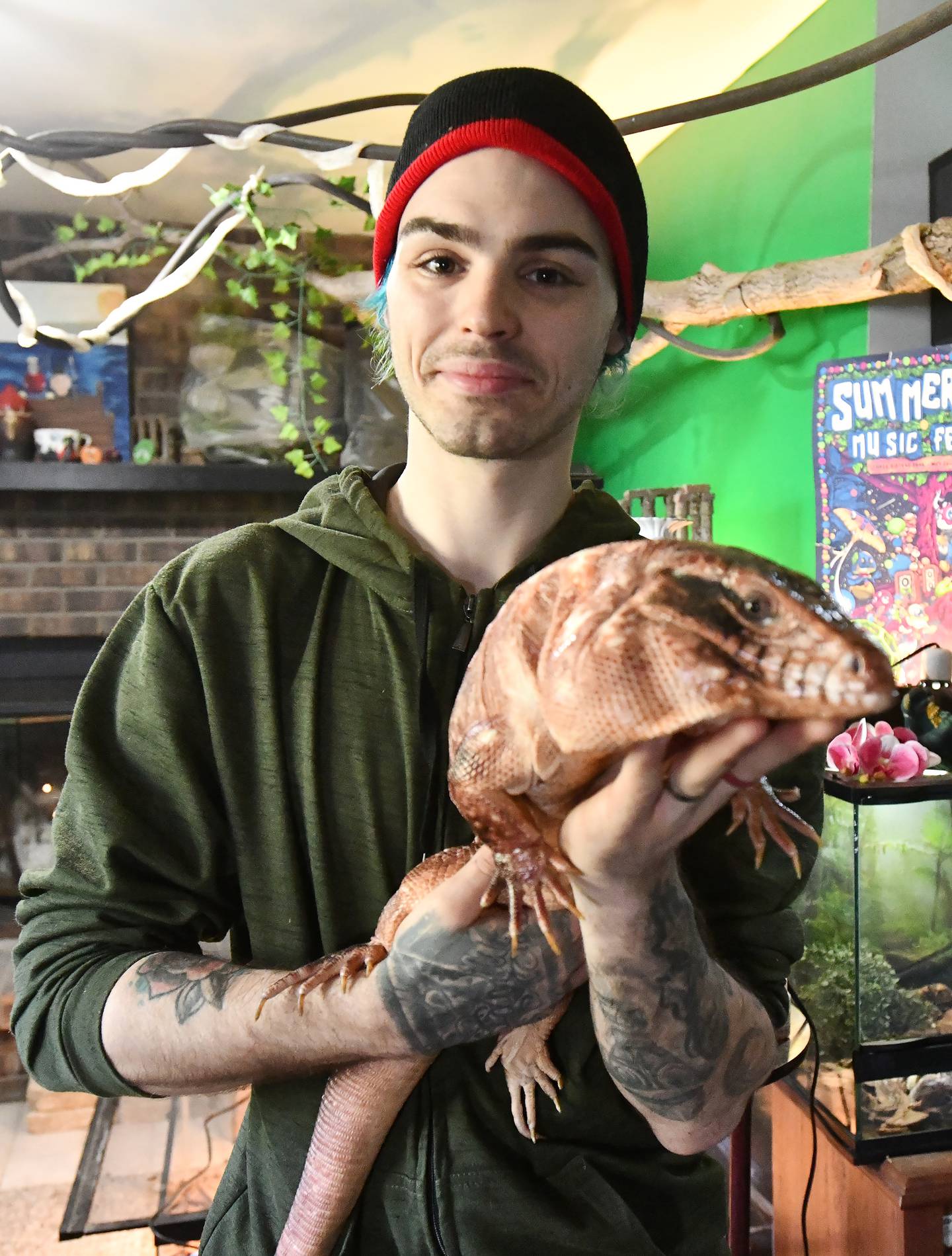 Niko Spizzirri, operator of Spizzirri Reptile Rescue & Rehab, stands in his Momence home-based rescue facility holding Barney, a large tegu lizard recovering from health problems in March 2024. The nonprofit seeks to provide rescue and rehabilitation for reptiles and other exotics, as well as serve in an educational role to the community.