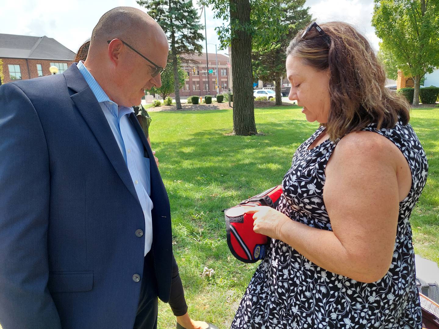 Therapy Dog trainer Annette Monge shows Streator United Way Board President Ben Hiltabrand the badges on the school therapy dogs' new vests presented Tuesday, Aug. 8, 2023.